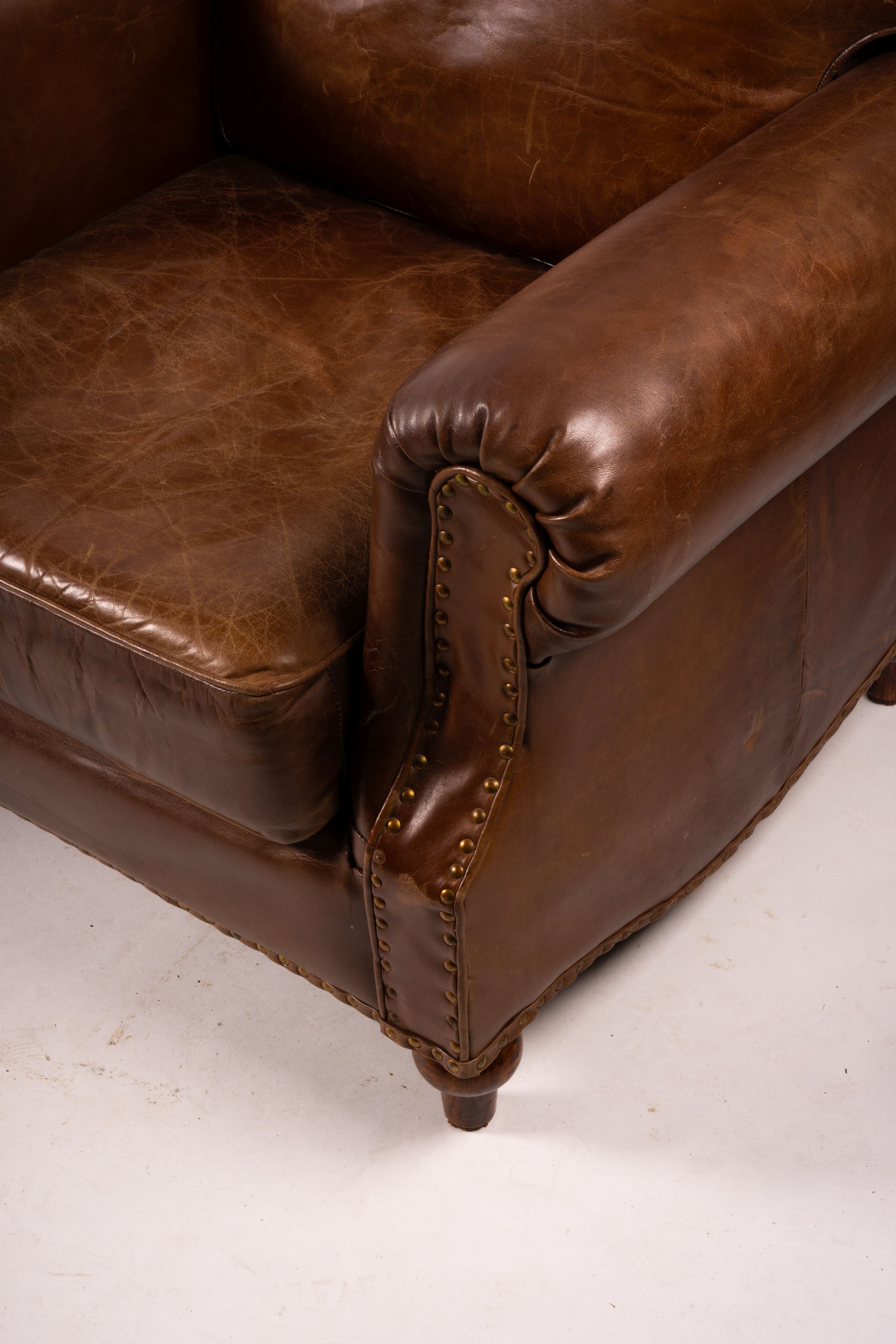 A pair of brown leather club armchairs, width 96cm, depth 80cm, height 90cm